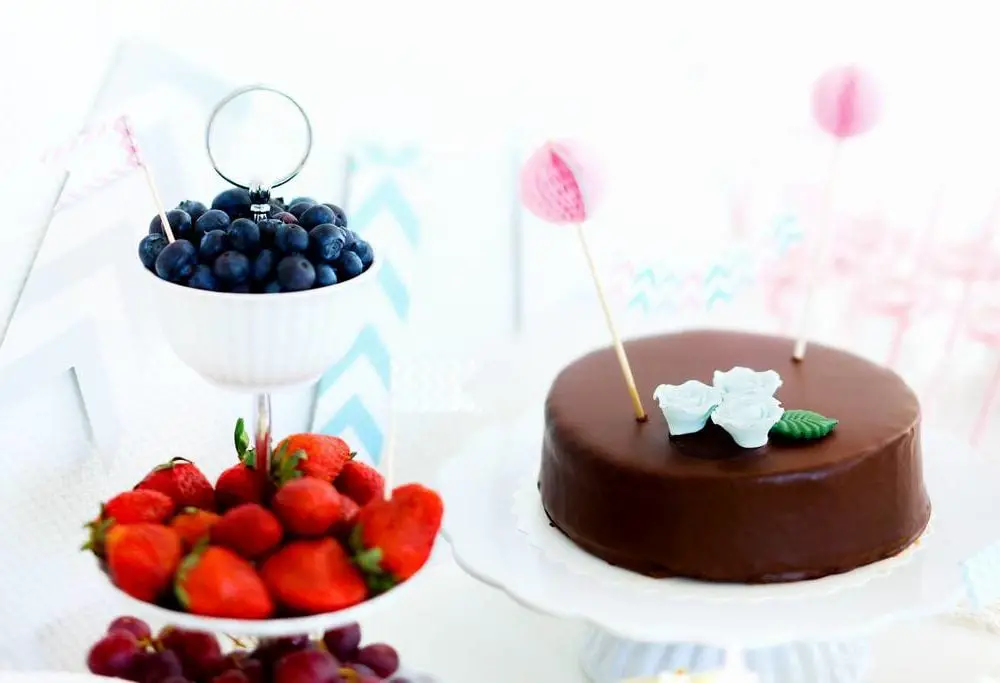 Blueberries, strawberries, grapes and a chocolate cake on a dess